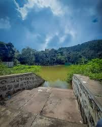 A peaceful countryside landscape with hilltop viewpoints, lush greenery, and a calm waterbody.