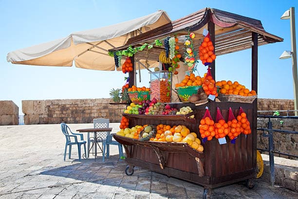 A vibrant roadside fruit stall displaying fresh fruits with seating and scenic viewpoints for travelers.