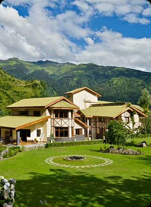 Green hillside resort surrounded by lush lawns and forested mountains creating a calm nature stay