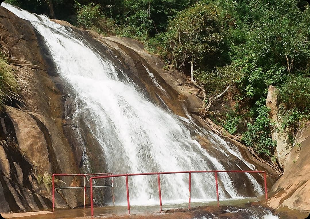 Masila Falls gently flowing over smooth rocky slopes with green forest surroundings offering a calm natural spot