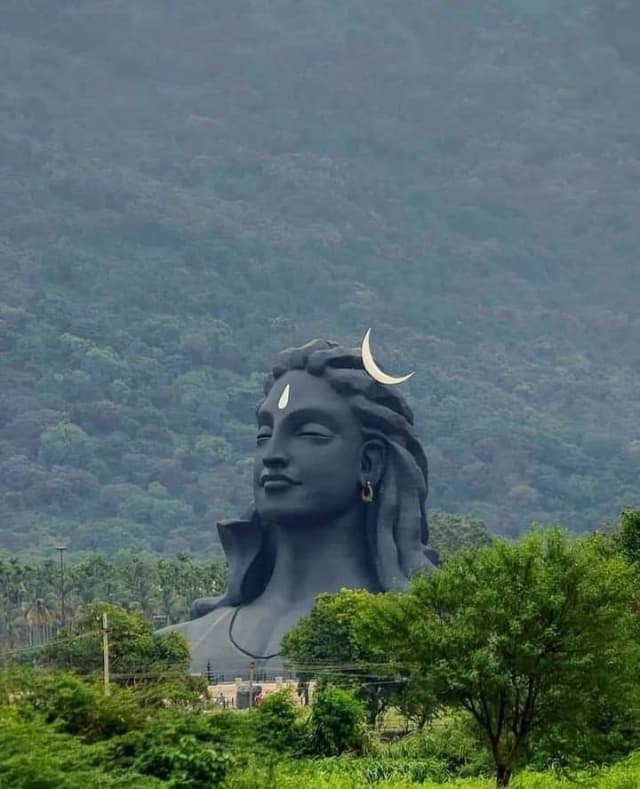 Adiyogi statue in Coimbatore with mountains in the backdrop and greenery across the open landscape.