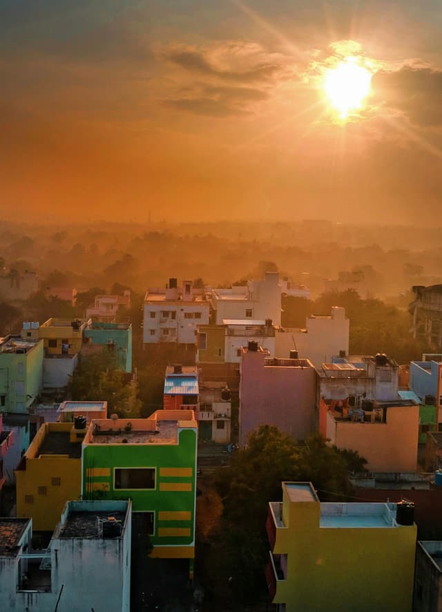Chennai city skyline lit by orange sunset hues with buildings glowing under warm evening light.